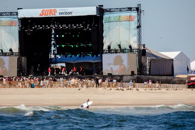Musicians on a large stage on a shoreline.
